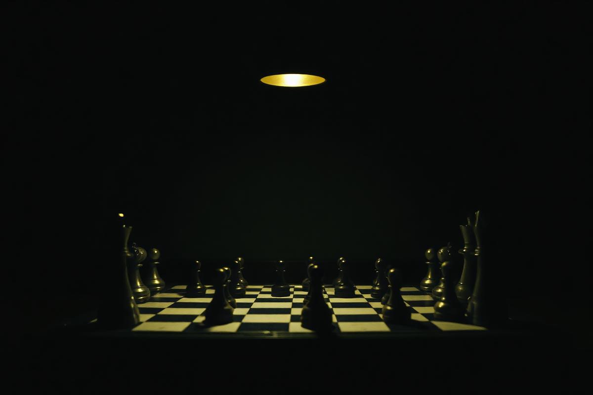A chess board mid-game lit by a single hanging bulb