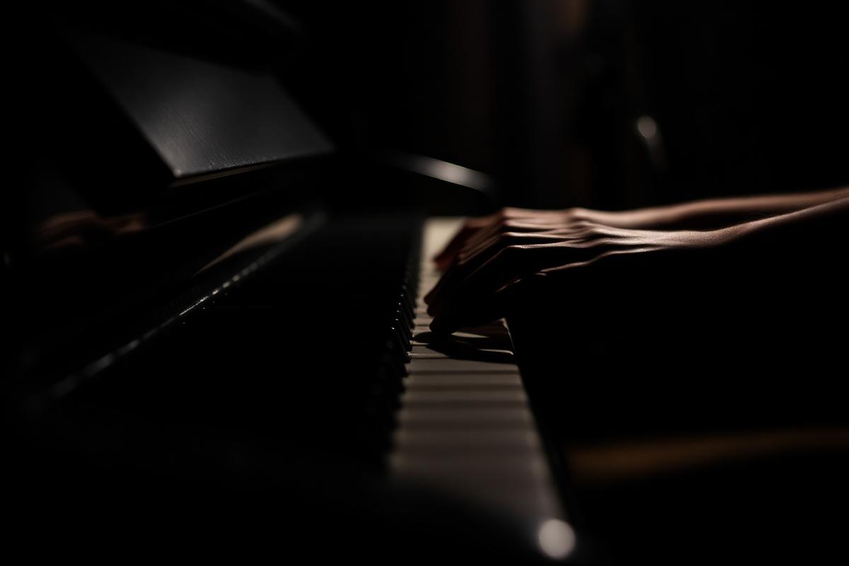 Hands practising scales on a piano keyboard in dim light