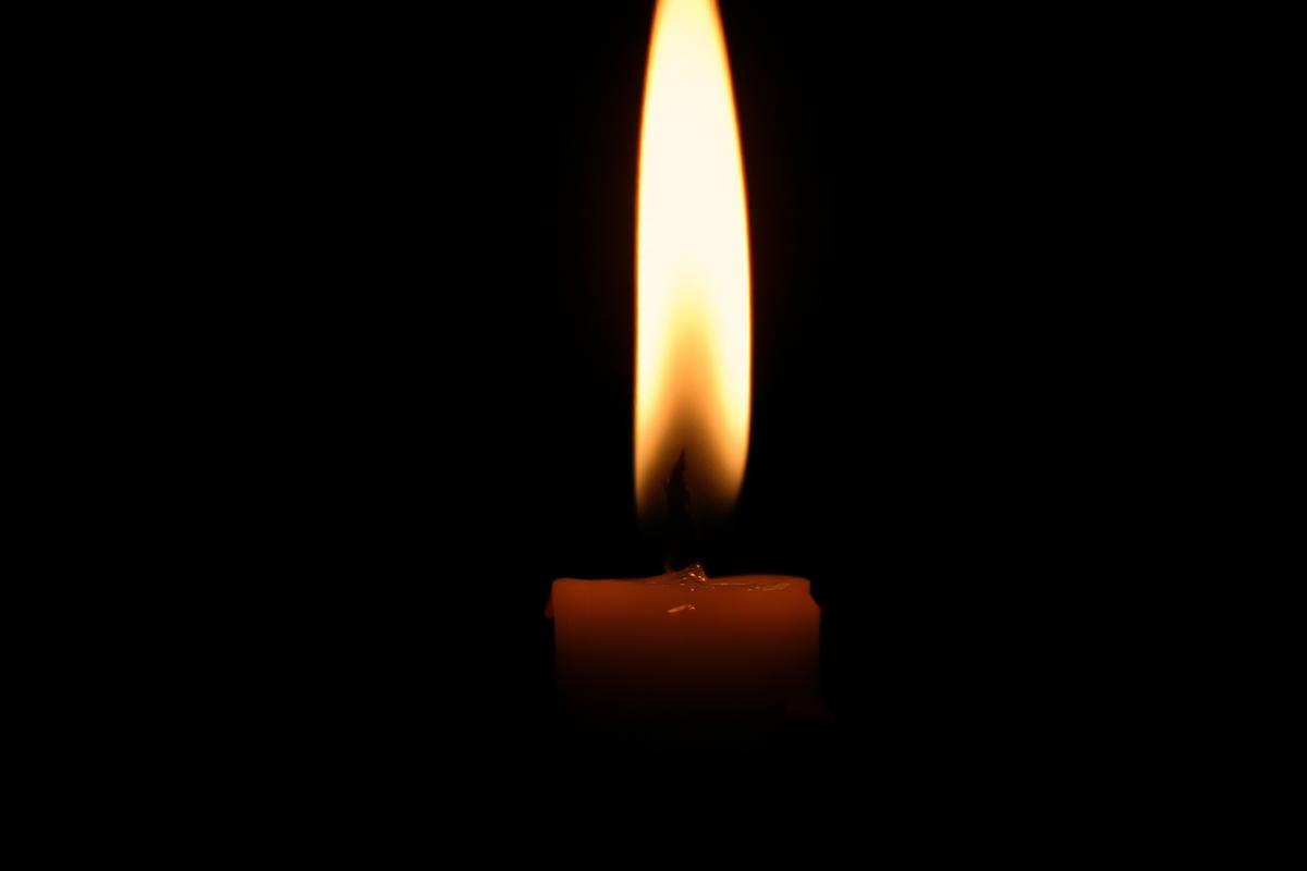 A single candle flame burning against deep black