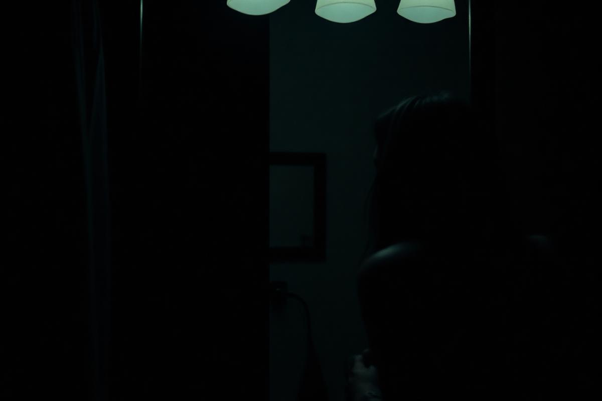 A person speaking quietly to their reflection in a dark mirror at night