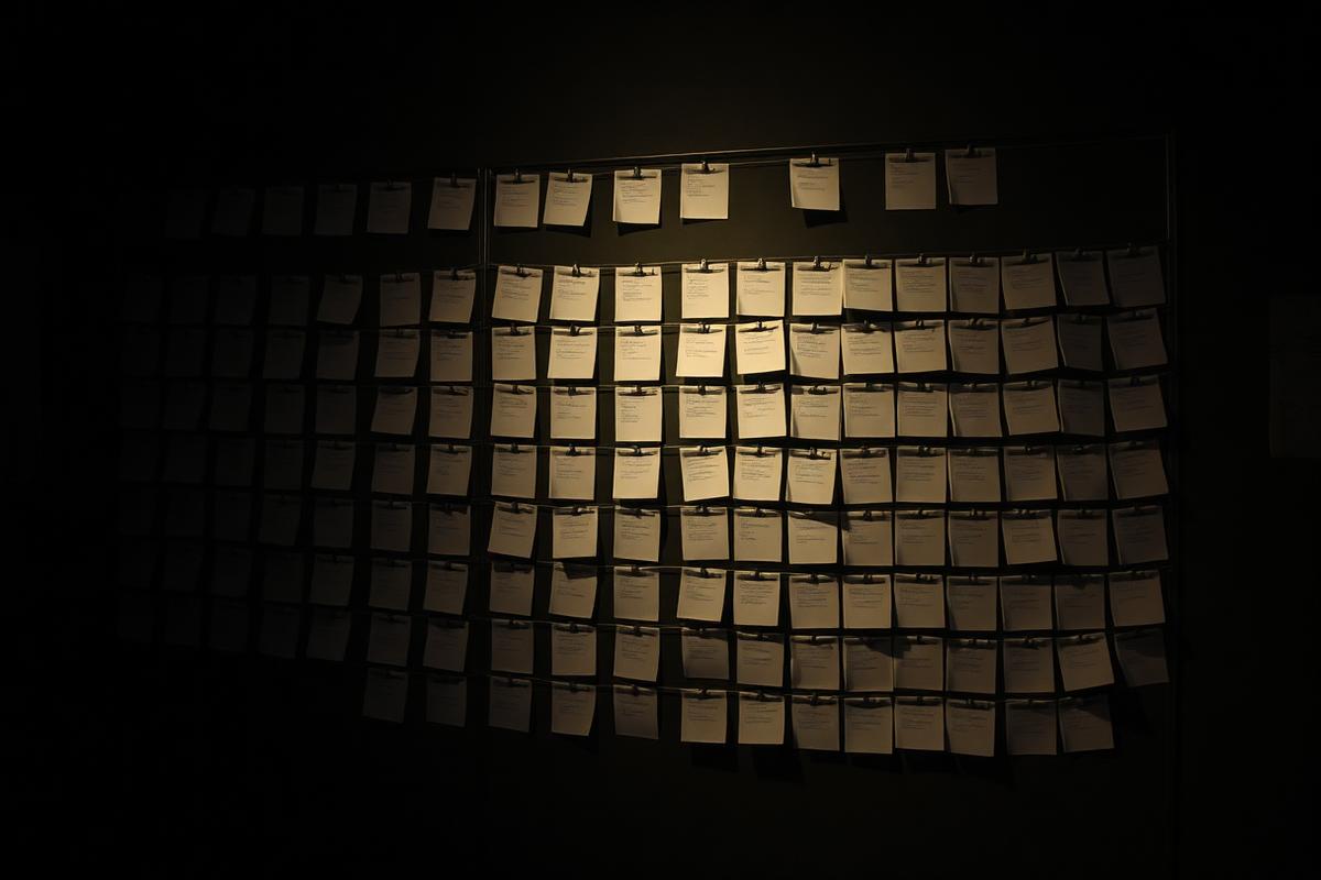 A wall of index cards and string forming a plan in a dim room