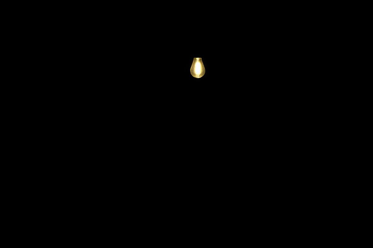Silhouetted people around a small table lit by a single hanging bulb